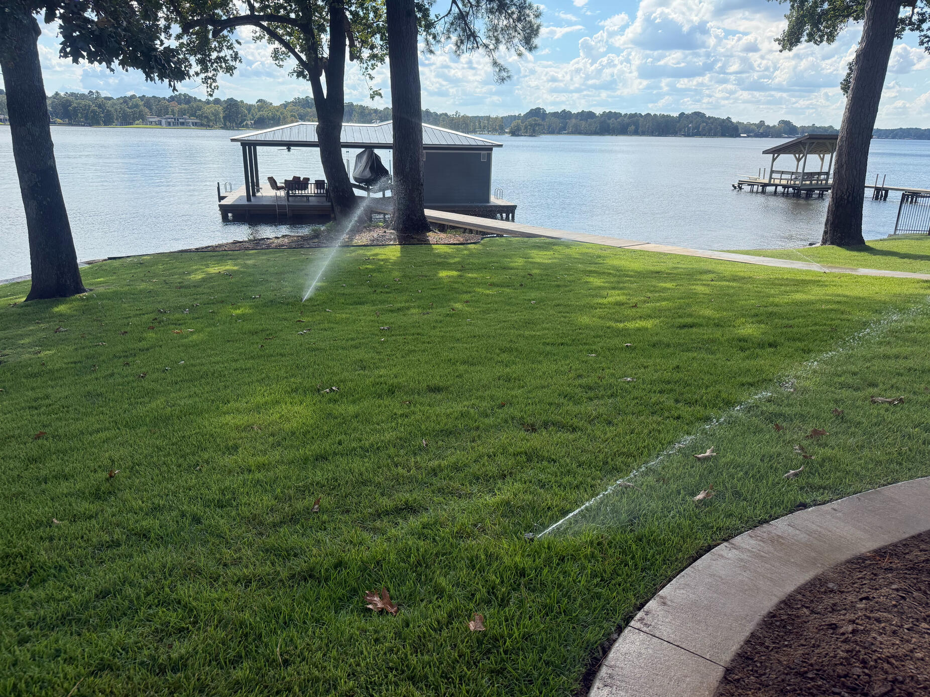Hans de Jong Irrigation Company Dual sprinkler heads watering a lakefront lawn at Lake Cherokee near Longview, Texas. Custom irrigation systems designed for efficient lake property watering in East Texas.